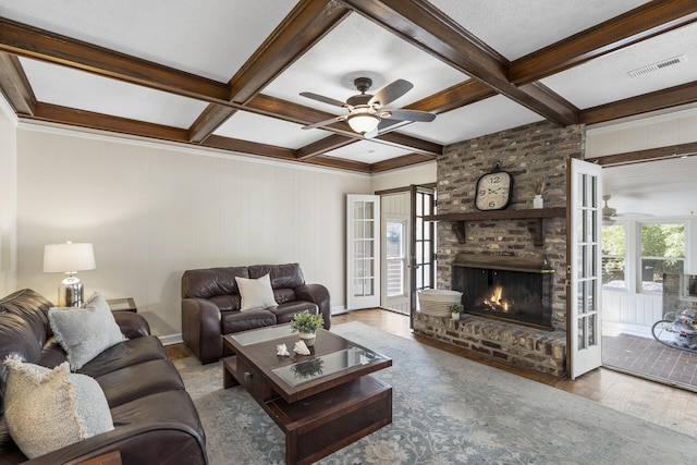 living room featuring coffered ceiling, a brick fireplace, visible vents, and beamed ceiling