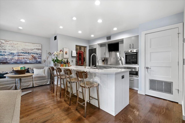 1481 Center Street Ext Unit 1102, Mount Pleasant, SC 29464 - kitchen featuring oven, a breakfast bar area, light countertops, dark wood-style floors, and recessed lighting