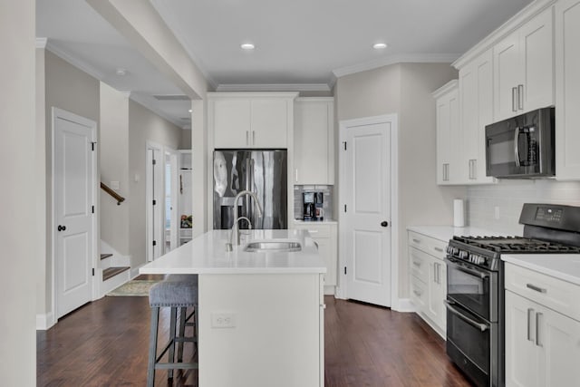 kitchen featuring range with two ovens, stainless steel fridge with ice dispenser, a kitchen island with sink, light countertops, and black microwave