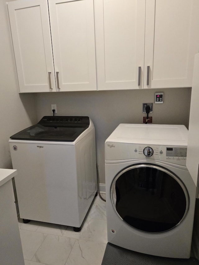 clothes washing area featuring marble finish floor, separate washer and dryer, and cabinet space