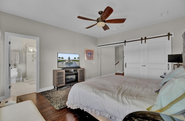 bedroom with a closet, a barn door, ceiling fan, wood finished floors, and baseboards