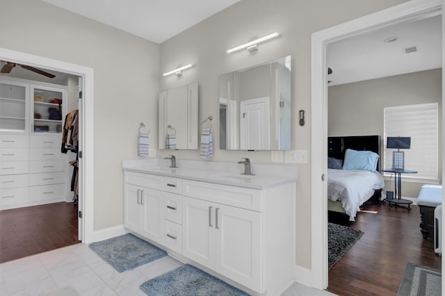 full bath with double vanity, a ceiling fan, wood finished floors, ensuite bathroom, and a sink