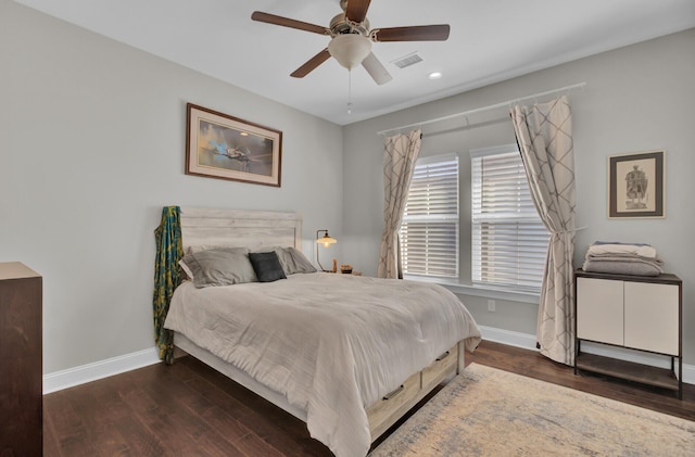 bedroom with a ceiling fan, dark wood-style flooring, visible vents, and baseboards