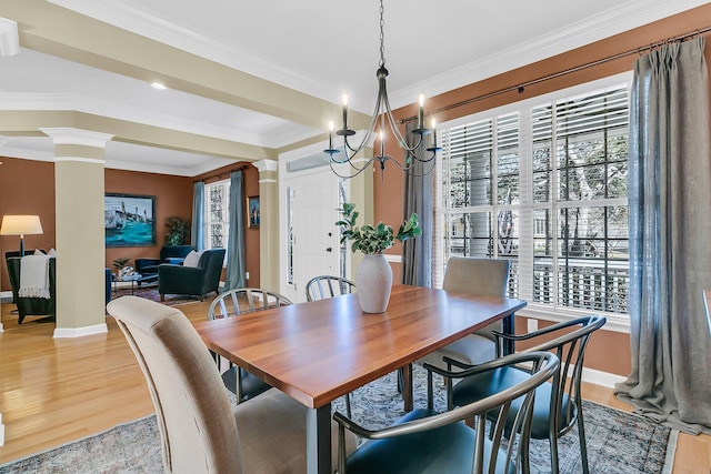 dining area with baseboards, light wood finished floors, decorative columns, and crown molding