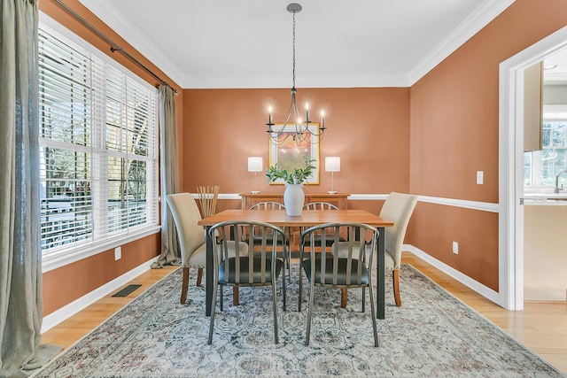 dining area with light wood finished floors, visible vents, a chandelier, and ornamental molding