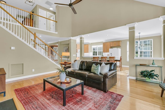 living room with light wood finished floors, stairway, visible vents, and ornate columns