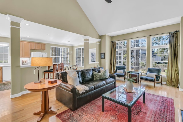 living area with high vaulted ceiling, recessed lighting, baseboards, light wood-type flooring, and ornate columns