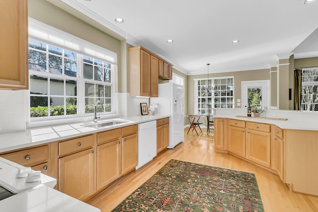 kitchen with white appliances, ornamental molding, a sink, light brown cabinets, and backsplash