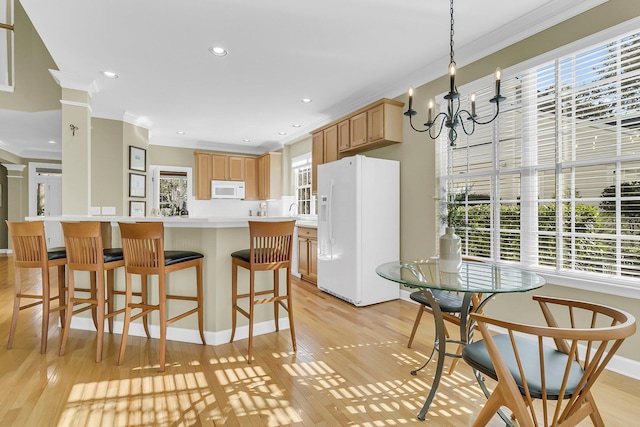 kitchen with light wood finished floors, light countertops, white appliances, and ornamental molding