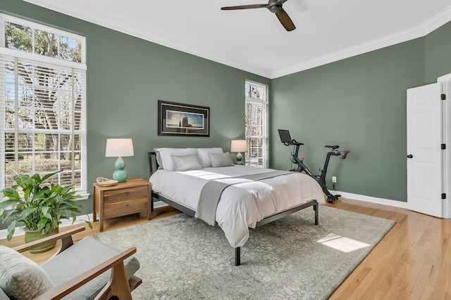 bedroom featuring baseboards, wood finished floors, a ceiling fan, and crown molding