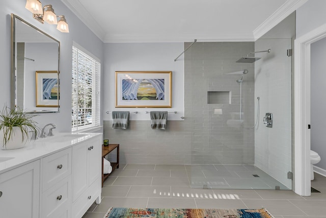 full bathroom featuring double vanity, tiled shower, toilet, ornamental molding, and a sink