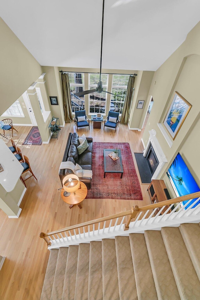 living area with baseboards, stairway, wood finished floors, and a fireplace with flush hearth