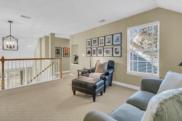 living area with carpet floors, visible vents, a notable chandelier, and an upstairs landing