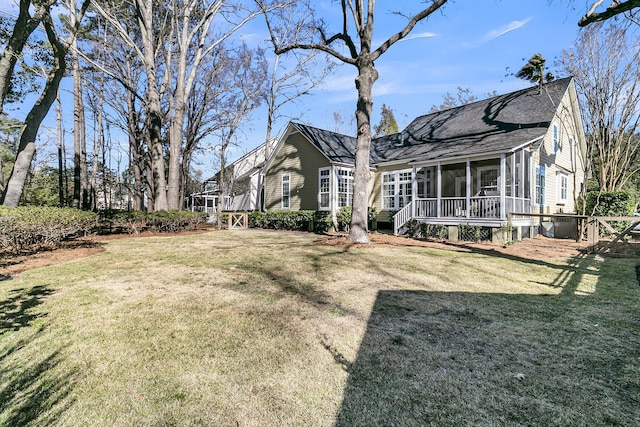 rear view of property featuring roof with shingles, a lawn, and a sunroom