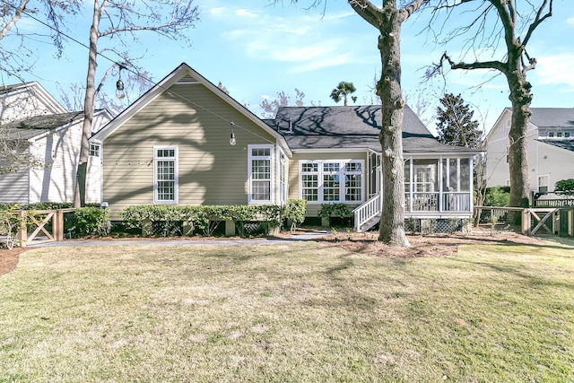 rear view of house featuring a yard, a gate, a sunroom, and fence