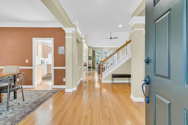 entrance foyer featuring light wood-style flooring, crown molding, decorative columns, and stairway