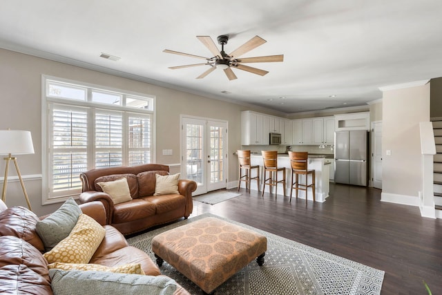 living room featuring french doors, ceiling fan, crown molding, and dark wood-type flooring