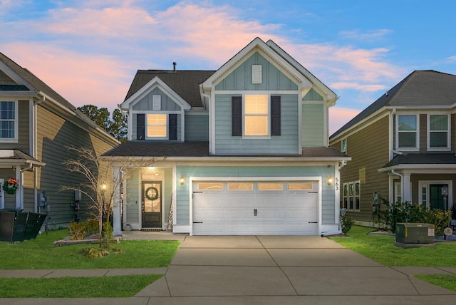 view of front of house with a garage, a yard, and central air condition unit