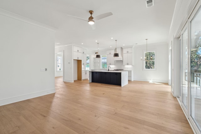 kitchen featuring visible vents, white cabinets, light countertops, premium range hood, and a sink