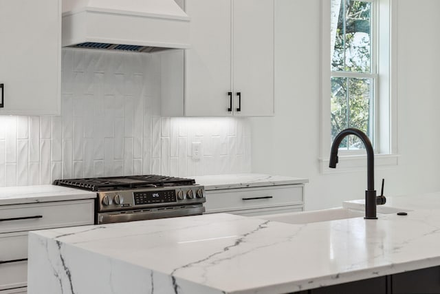 kitchen with white cabinets, premium range hood, stainless steel range with gas stovetop, and tasteful backsplash