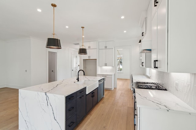 kitchen with appliances with stainless steel finishes, white cabinets, a sink, and backsplash