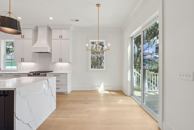 kitchen with visible vents, backsplash, custom exhaust hood, light wood finished floors, and stainless steel range with gas stovetop