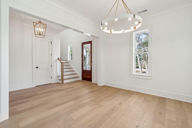 foyer entrance with a chandelier, visible vents, baseboards, ornamental molding, and light wood-type flooring