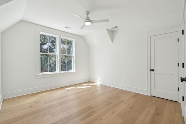 additional living space with light wood-type flooring, visible vents, vaulted ceiling, and baseboards