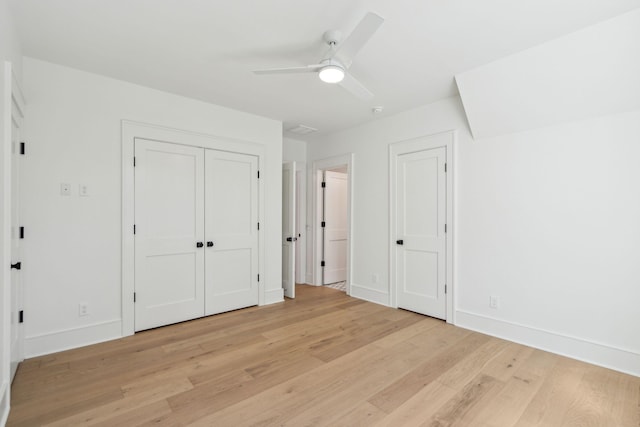 unfurnished bedroom featuring light wood-style floors, a ceiling fan, baseboards, and multiple closets