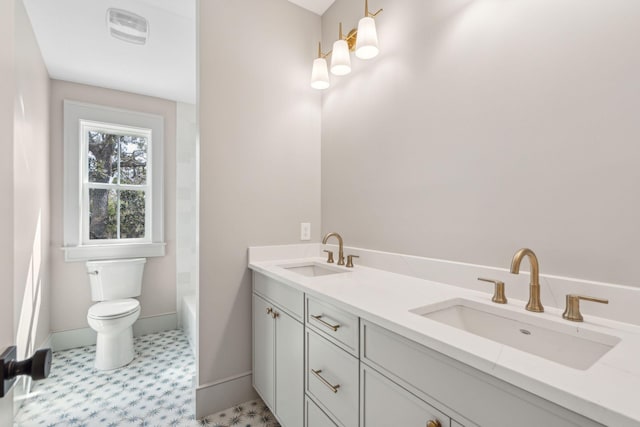 full bathroom with baseboards, a sink, toilet, and double vanity