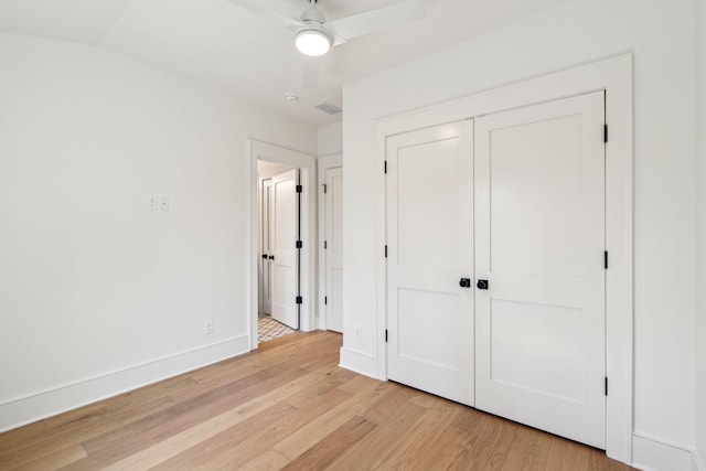 unfurnished bedroom featuring light wood finished floors, a closet, visible vents, a ceiling fan, and baseboards