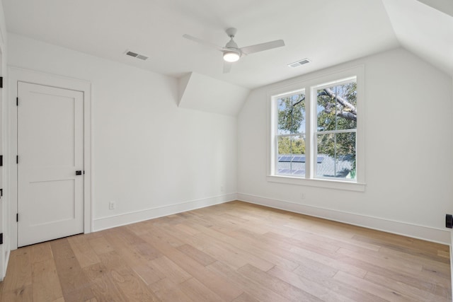 additional living space with light wood-type flooring, visible vents, vaulted ceiling, and baseboards