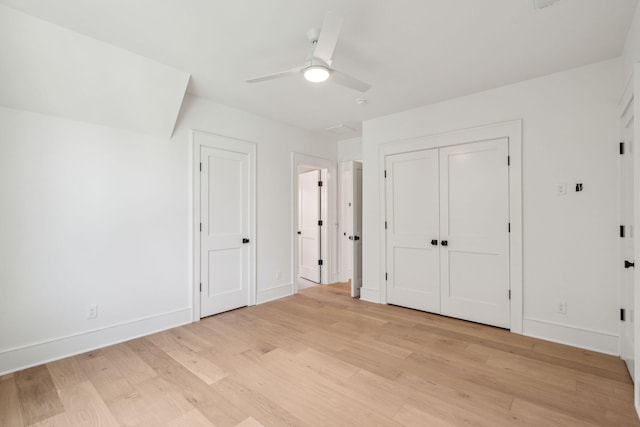 unfurnished bedroom with light wood-style floors, ceiling fan, baseboards, and multiple closets