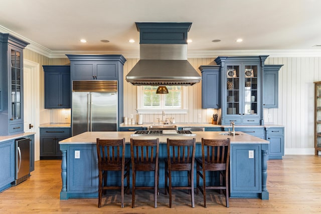 kitchen featuring crown molding, a center island with sink, stainless steel appliances, and blue cabinets