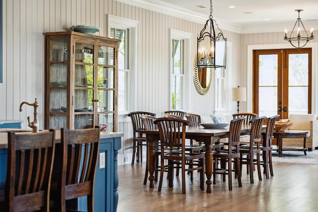 dining space with french doors, ornamental molding, dark wood finished floors, and a chandelier
