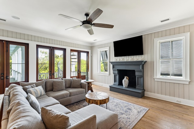 living room with french doors, visible vents, crown molding, baseboards, and a fireplace with raised hearth