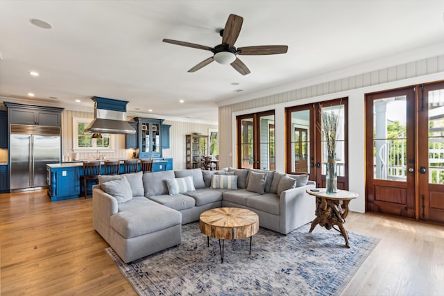 living room with ornamental molding, recessed lighting, light wood-type flooring, french doors, and a ceiling fan
