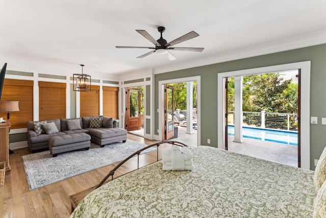 bedroom with access to outside, ornamental molding, wood finished floors, and a notable chandelier