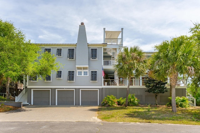 view of front of home with an attached garage, driveway, and a balcony