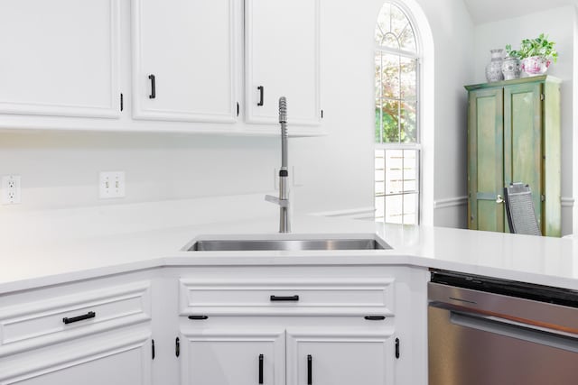 kitchen featuring a sink, dishwasher, white cabinets, and light countertops