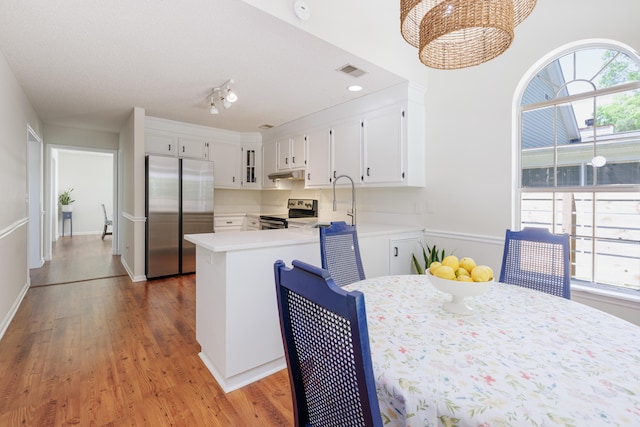 kitchen with visible vents, light countertops, white cabinets, stainless steel appliances, and light wood-style flooring
