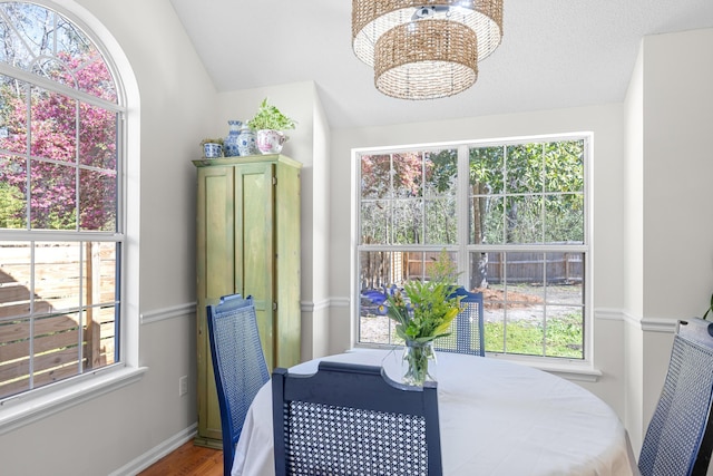 dining area featuring baseboards, lofted ceiling, wood finished floors, and a chandelier