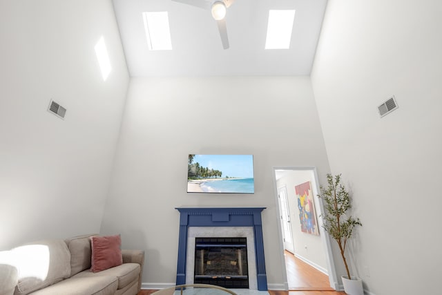 living room with visible vents, wood finished floors, ceiling fan, high vaulted ceiling, and a premium fireplace
