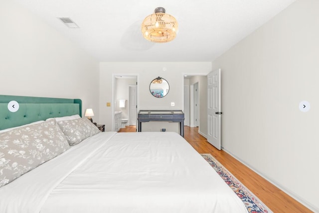 bedroom with visible vents, wood finished floors, and ensuite bath