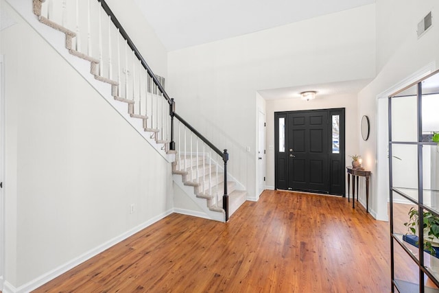entryway featuring baseboards, wood-type flooring, stairs, and visible vents