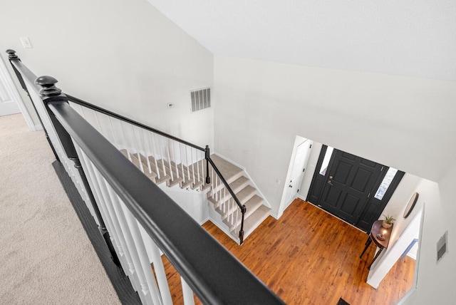 foyer featuring carpet flooring, high vaulted ceiling, and visible vents