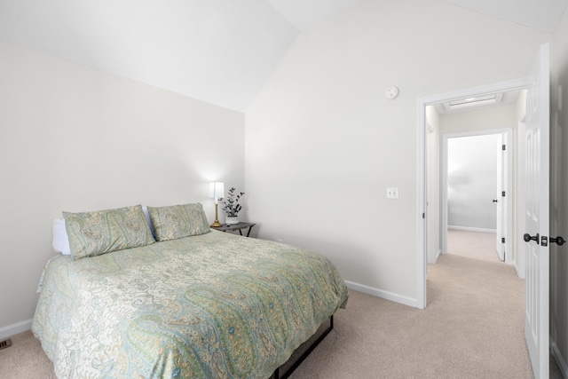 bedroom with baseboards, vaulted ceiling, and light colored carpet