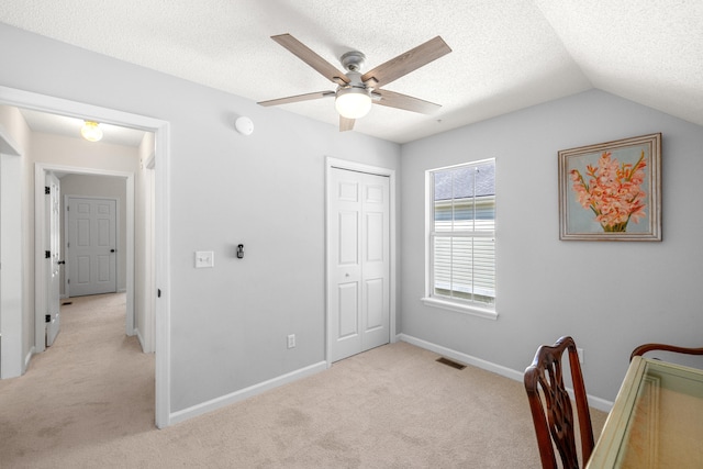 office space with light colored carpet, a textured ceiling, a ceiling fan, baseboards, and visible vents