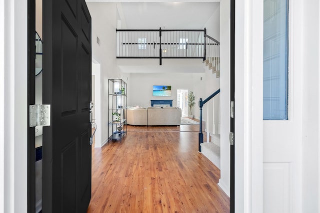 entryway featuring visible vents, stairs, a towering ceiling, baseboards, and light wood-style flooring