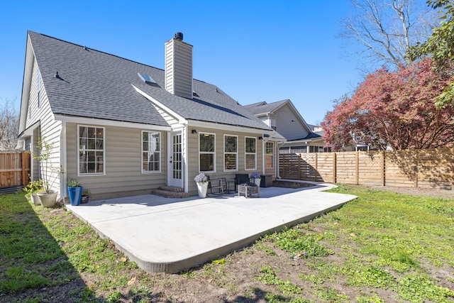 back of house with a fenced backyard, a shingled roof, a chimney, and a patio area